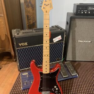 Full-view shot of a vintage red Fender Lead II electric guitar on a stand. The guitar has a maple neck, a black pickguard, and two single-coil pickups. In the background are a VOX Valvetronix amplifier, a Blackstar cabinet, and VOX multi-effects pedals.